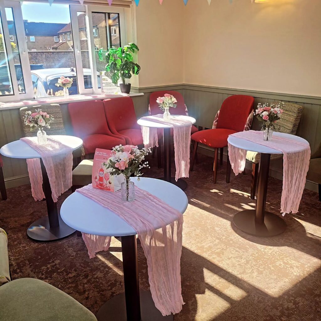 Tables dressed with pink runners and flowers in the Orangery