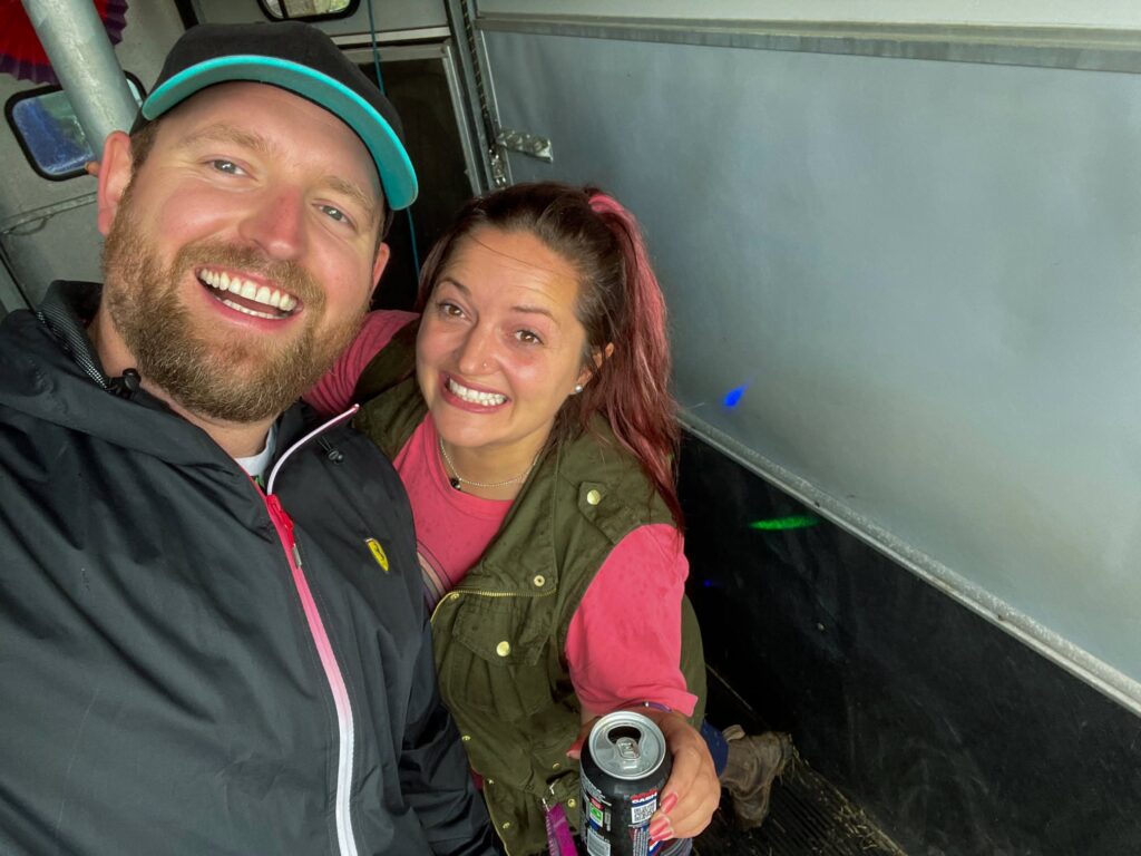 Two regulars smiling in the rain at a garden party