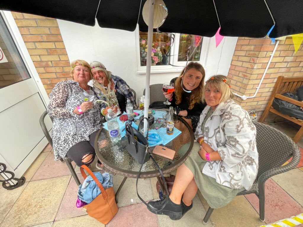 Four friends in flower crowns under a parasol on the patio